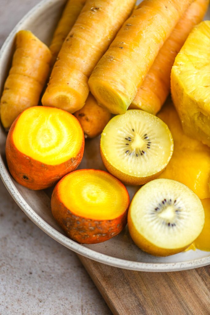 yellow carrots, golden beets, mango, pineapple and golden kiwi on a plate