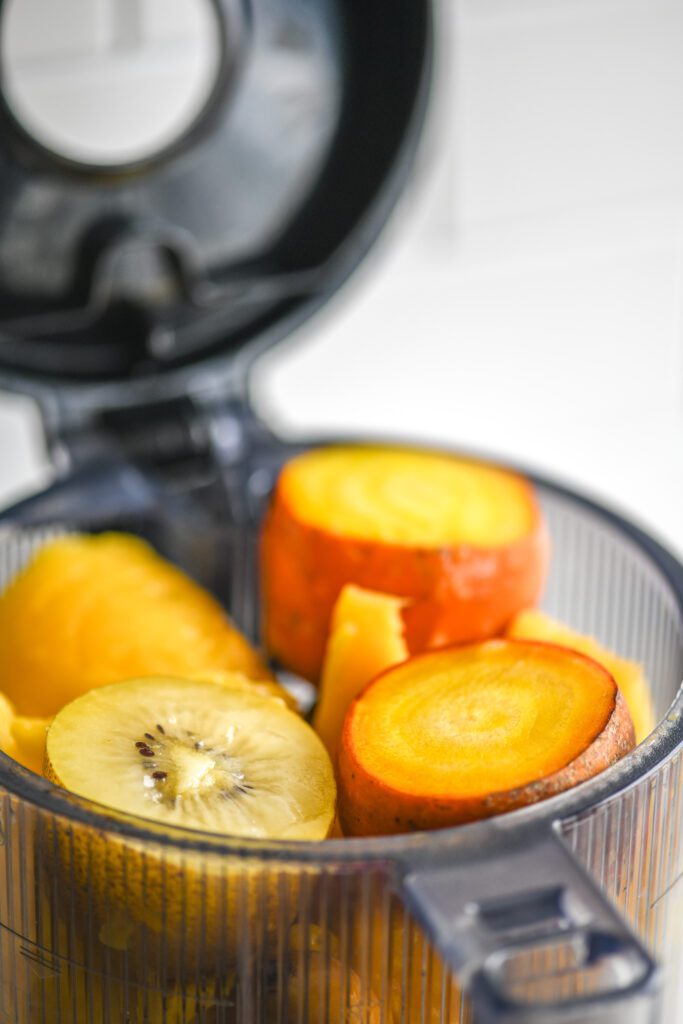 yellow carrots, golden beets, mango, pineapple and golden kiwi in a juicer